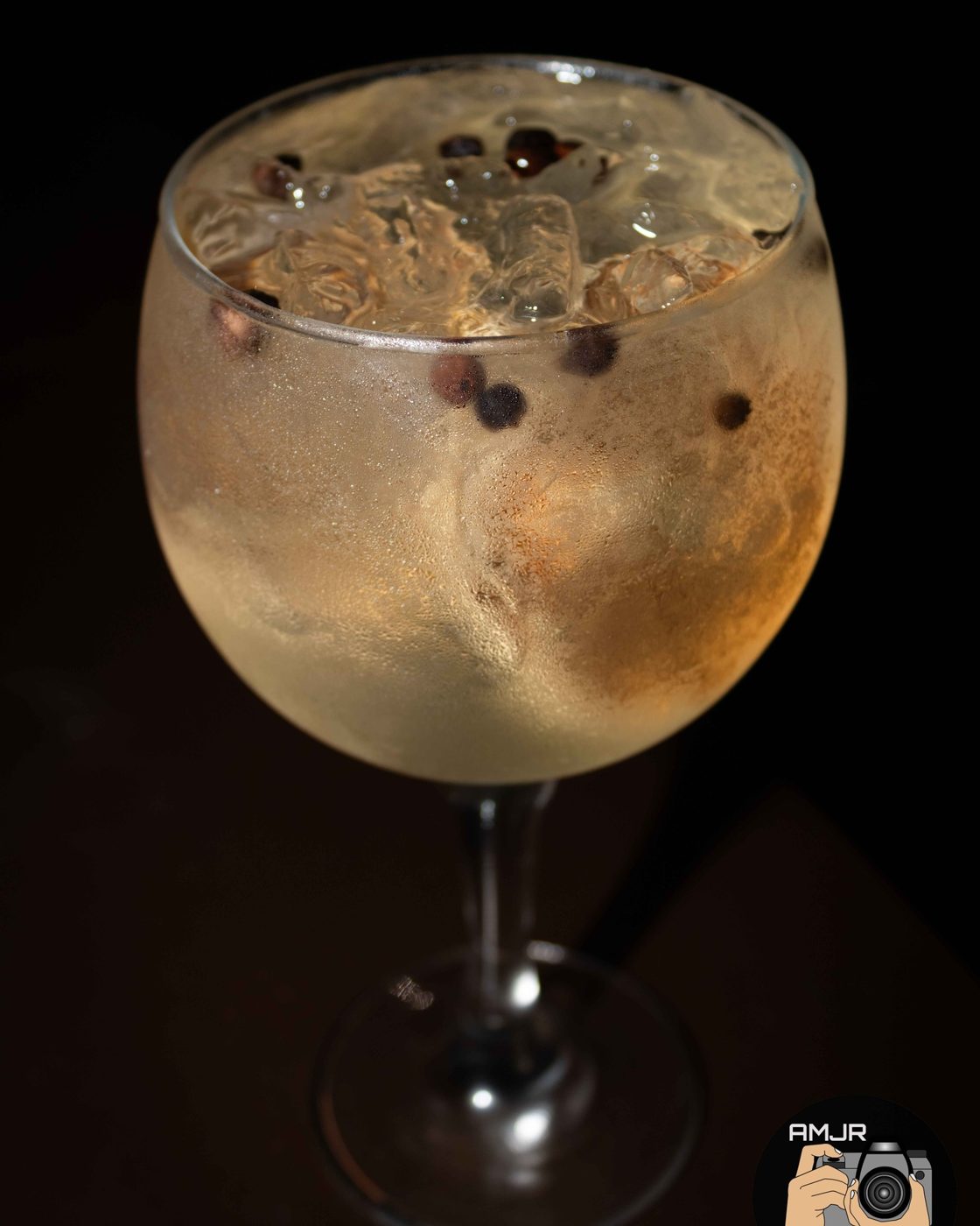 Taça de gin tônica com especiarias em fundo escuro