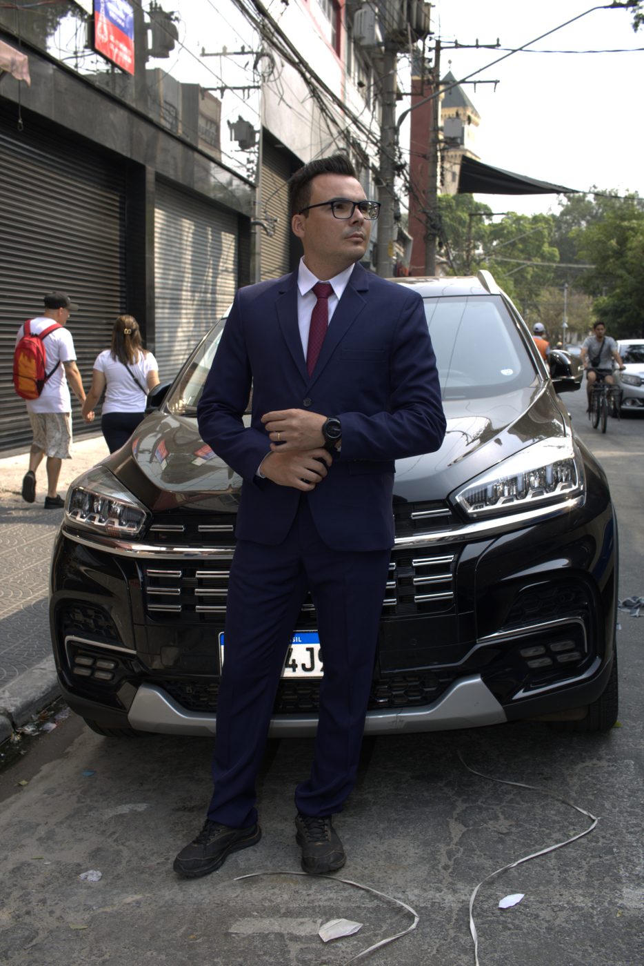 Modelo de terno azul-marinho ao lado de carro